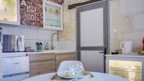 Een compacte keuken met een koelkast, een spoelbak en een eethoek met een tafel voor twee personen.