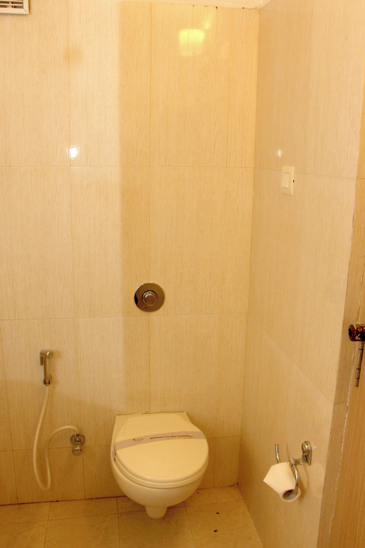 A small, enclosed bathroom with a toilet, a shower, and a towel rack.