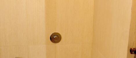 Une petite salle de bain fermée, comprenant des toilettes, une douche et un porte-serviettes.