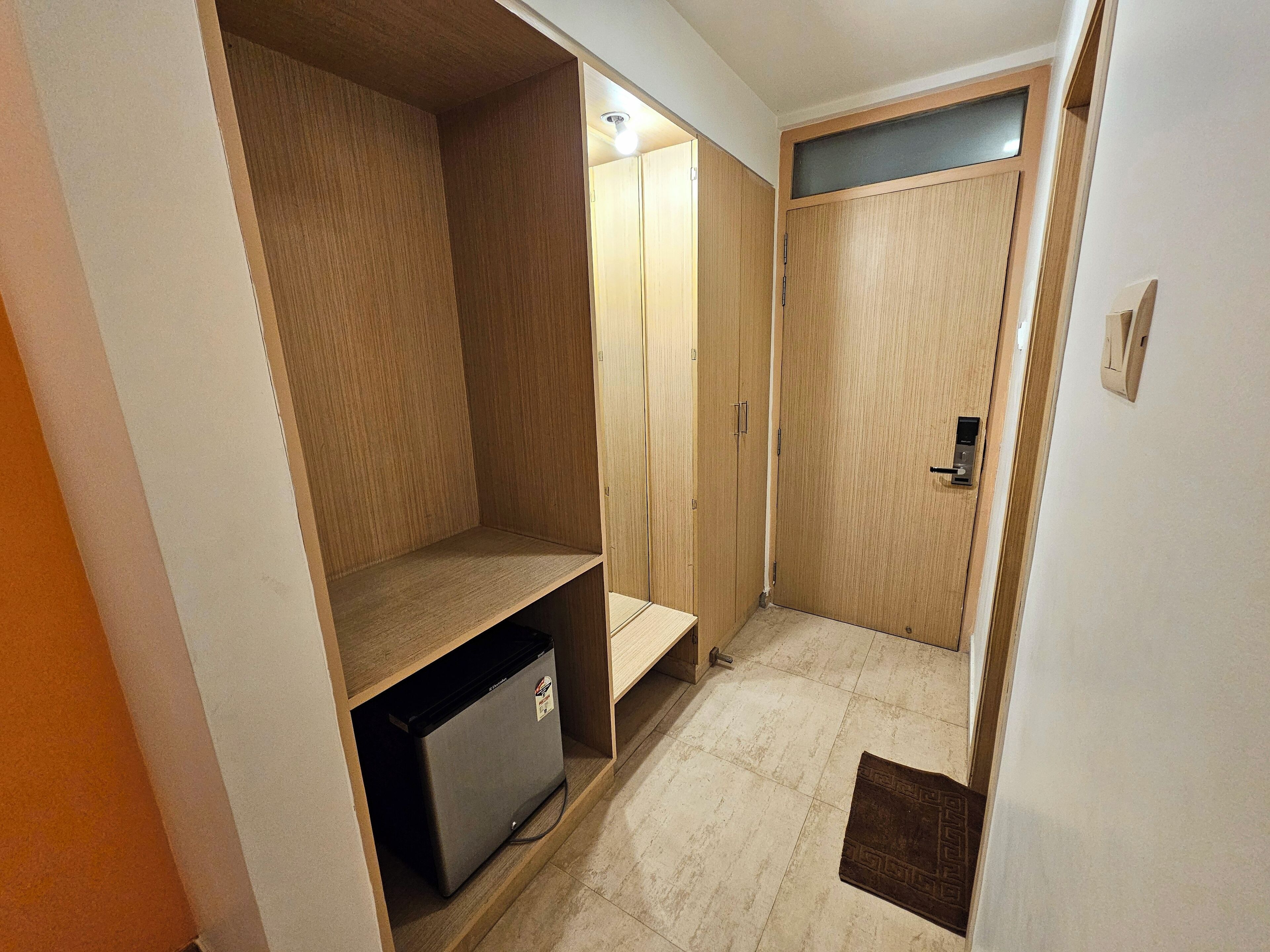 A walk-in closet with wooden shelving, a small refrigerator, and a door with a handle.
