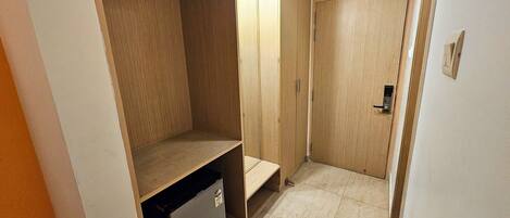 A walk-in closet with wooden shelving, a small refrigerator, and a door with a handle.