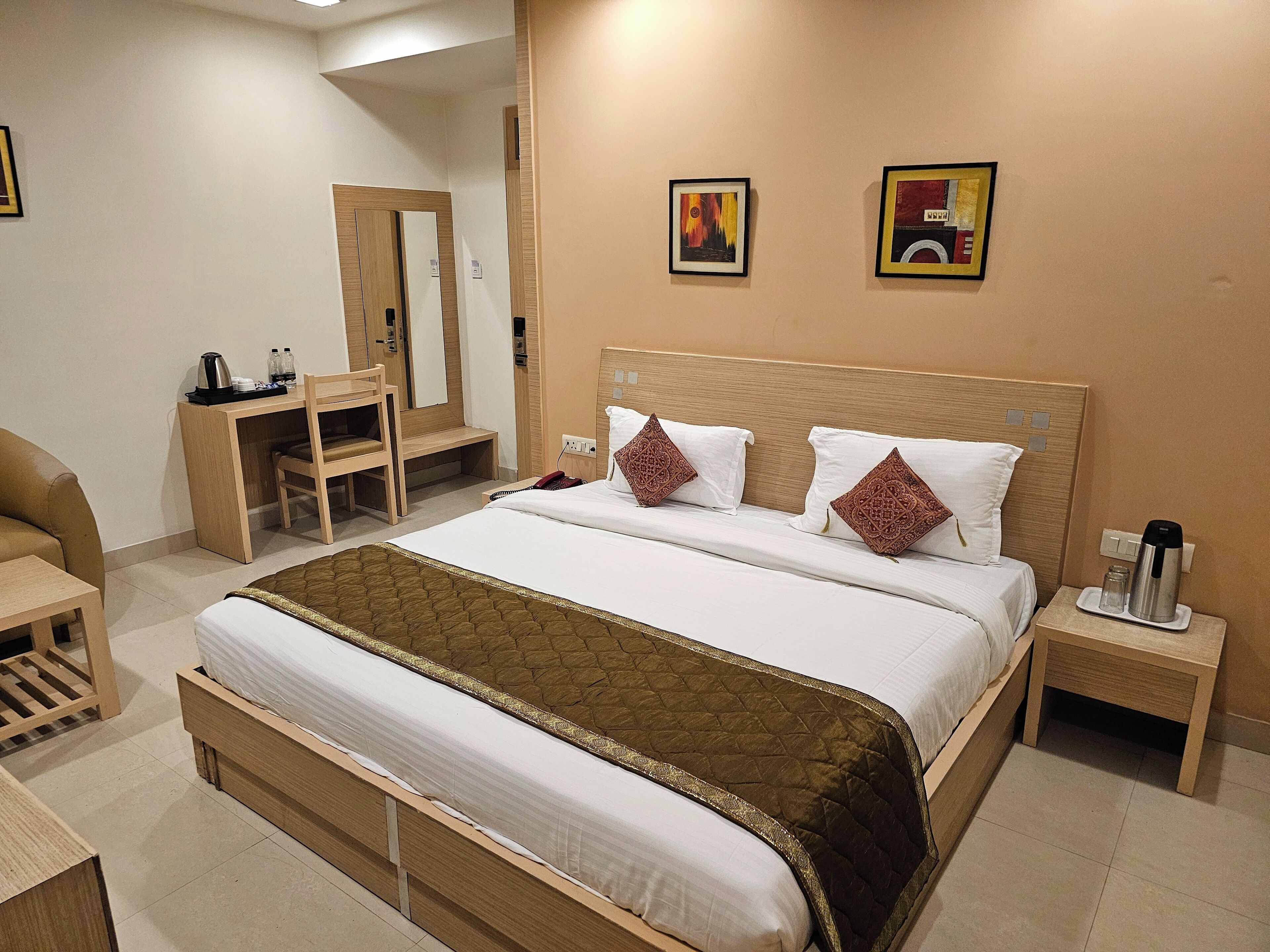 A hotel room with a bed, bedside table, chair, desk, and a mirror.