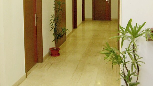 A corridor with doors, potted plants, and recessed lighting. - Hotel Crown Palace (Prayagraj)
