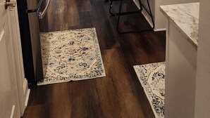 Et moderne køkken med en central ø, barstole og et spiseområde med sofa og bord.