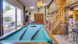 A pool table in a room with wooden walls and a large window.