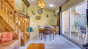 A wooden interior with a dining area, a staircase, and a large window.