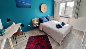 Une chambre à coucher avec un lit, un bureau, une chaise, une fenêtre et une vue sur l’extérieur.