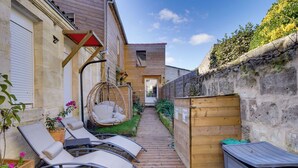 A wooden deck with lounge chairs, a hanging chair, and a small garden area with plants and a wooden fence. - Villa Pauill'art - Marco Polo  (Pauillac)