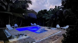 Una piscina all'aperto con lettini bianchi e un solarium piastrellato.