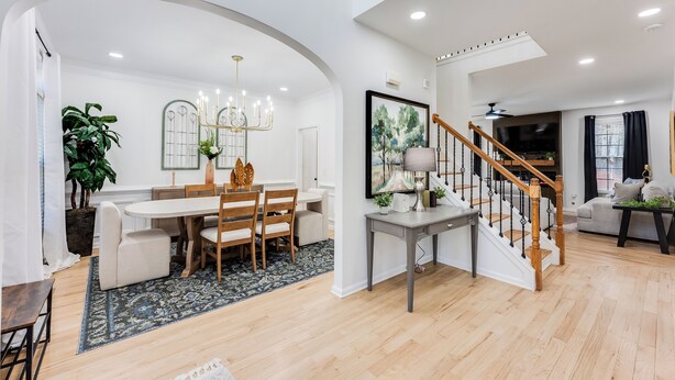 Un vaste espace de vie comprenant une table à manger, des chaises, un escalier et une grande fenêtre.