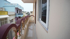 Un balcon étroit doté d’une balustrade, d’une fenêtre et offrant une vue sur les bâtiments voisins.