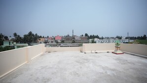 A rooftop terrace with a view of a cityscape, including buildings and a tower. - Sadhu Inn (Puri)