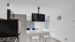 A compact kitchen with a stove, microwave, and a small dining area with two bar stools.