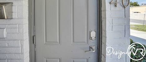A white door with a keyhole and a doorbell, a mailbox, and a house number '40' on a white brick wall.