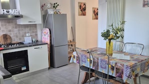 Eine moderne Küche mit Einbauofen, Kühlschrank und Essbereich mit Tisch und Stühlen.