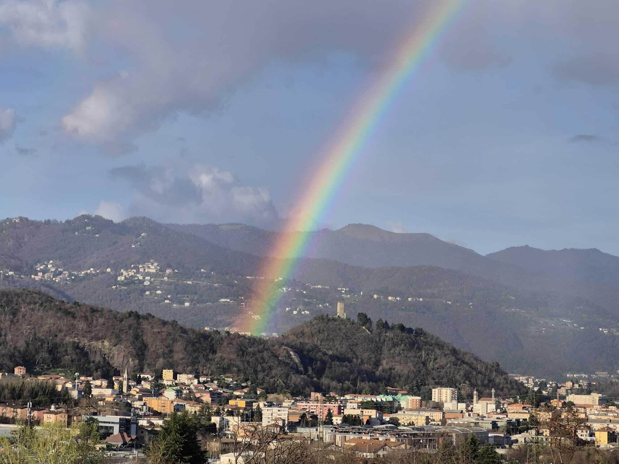 Eine Stadtansicht mit einem Regenbogen über den Bergen.