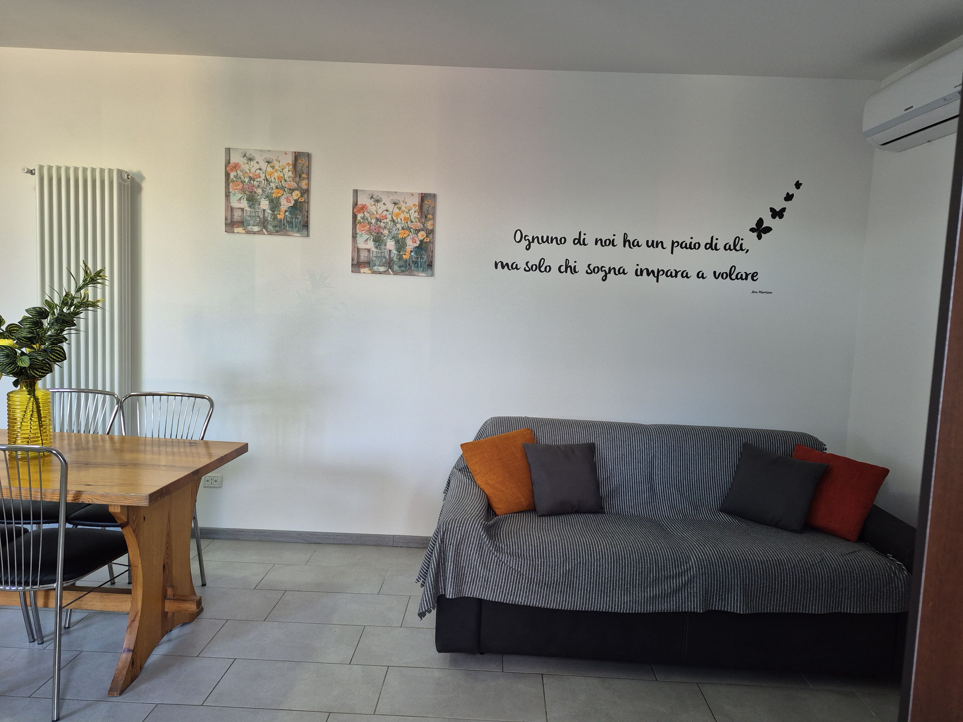 Un soggiorno moderno con zona pranzo, che include un divano, un tavolo e due opere d'arte a parete.
