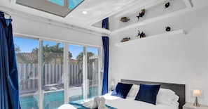 A hotel room with a bed, a nightstand, a lamp, and a view of a swimming pool through large glass doors. - Unit C Sea&i Private House Near Deerfield Beach (Deerfield Beach)