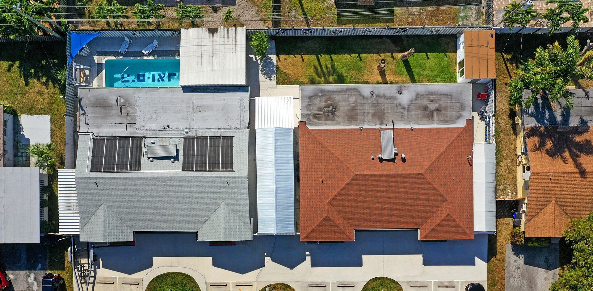 An aerial view of a building with a swimming pool, multiple windows, and a rooftop with a chimney.