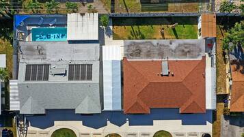An aerial view of a building with a swimming pool, multiple windows, and a rooftop with a chimney.