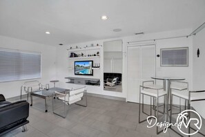 A modern living room with a flat-screen TV, a sofa, a coffee table, and a dining area with chairs and a glass-top table. - Unit C Sea&i Private House Near Deerfield Beach (Deerfield Beach)