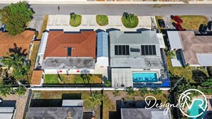 Vista aérea de um edifício com piscina, estacionamento e vegetação ao redor.