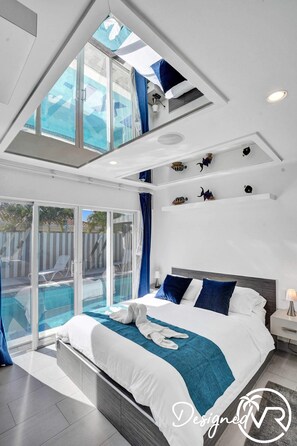 Una habitación de hotel moderna con una cama grande, un balcón con piscina y un tragaluz.