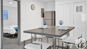 Une chambre d’hôtel moderne équipée d’un coin repas, d’un lit, d’une horloge et d’un réfrigérateur.