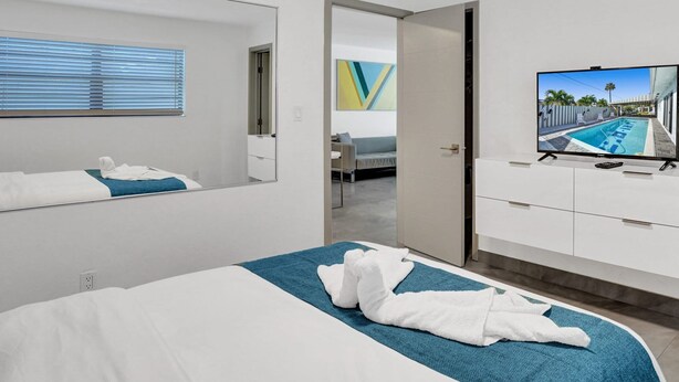 Une chambre d’hôtel moderne avec un grand lit, une télévision et une vue sur une piscine.