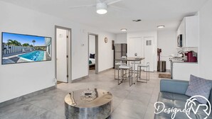 Un salon moderne avec vue sur la piscine, un coin repas et une kitchenette.
