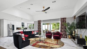 Una sala de estar moderna con un sofá modular, una mesa de centro redonda y un ventilador de techo.