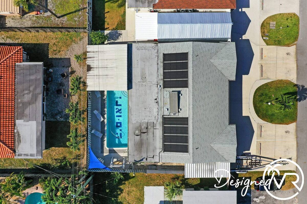 Vista aérea de un edificio con piscina en la azotea, rodeado de vegetación y edificios adyacentes.