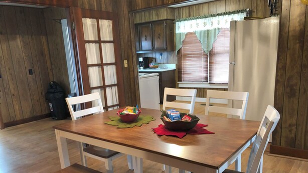 A dining area with a wooden table, white chairs, and a red placemat.