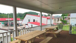 A covered outdoor area with picnic tables and a view of a gas station and a dairy shack in the background.