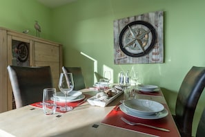 Enjoy meals in this dining area with a table set for a meal, featuring a wooden cabinet and a rustic compass artwork.