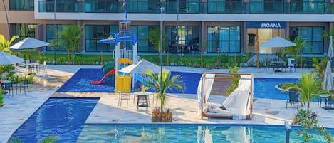 A hotel pool area with a slide, lounge chairs, umbrellas, and a Moana restaurant in the background.