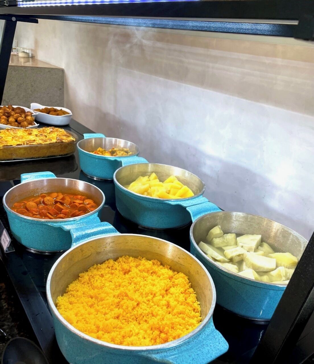 Een buffet met diverse gerechten, zoals rijst, wortelen en aardappelen.