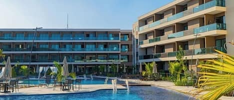 A hotel with a swimming pool, multiple balconies, and a modern architectural design.