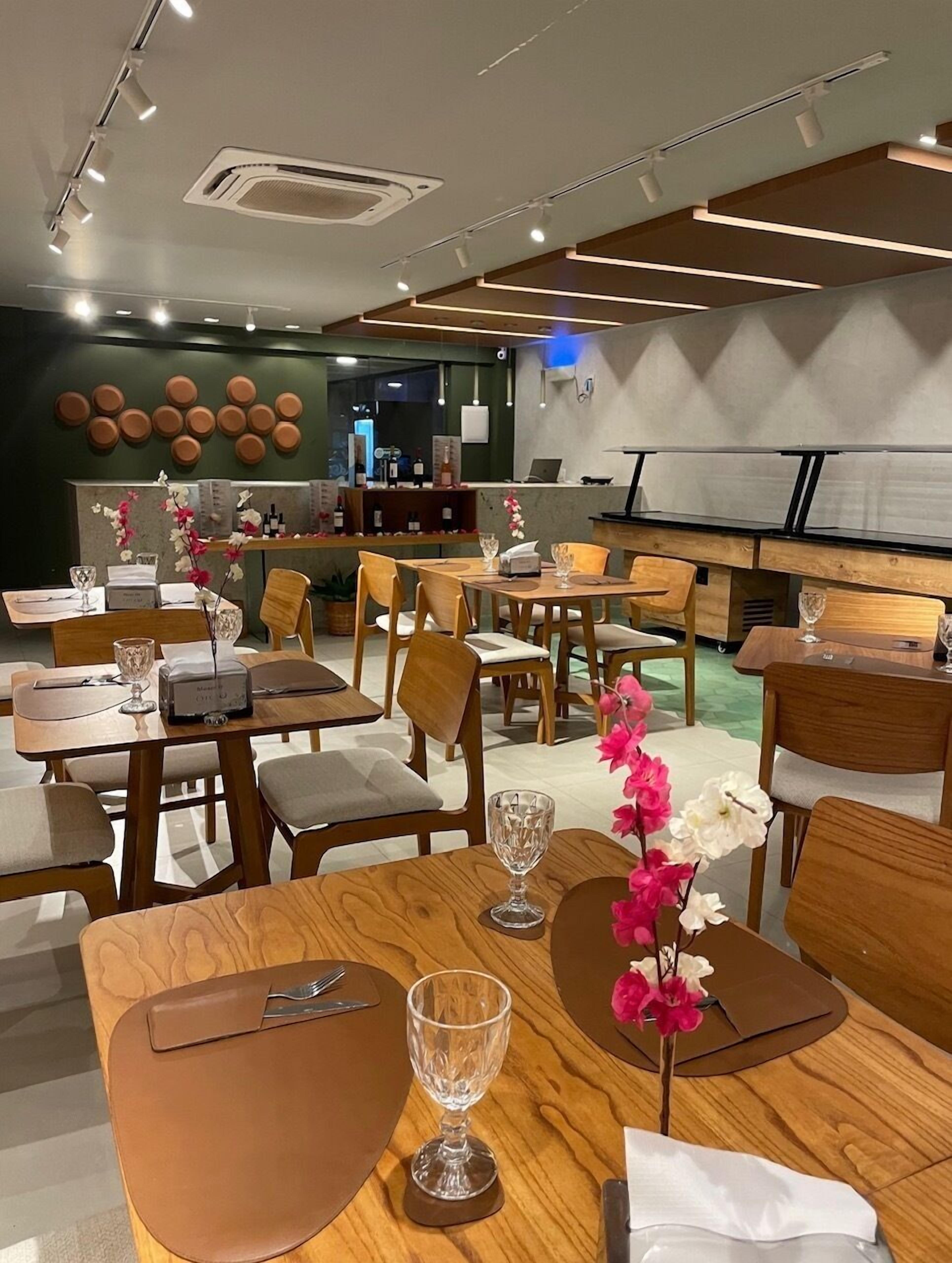Un restaurante moderno con mesas y sillas de madera, una zona de bar y elementos decorativos en las paredes.
