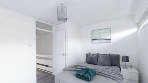 A bedroom with a bed, a nightstand, a lamp, and a painting on the wall. - Karazo Property- Luxury 2 bed in Croydon (Croydon)