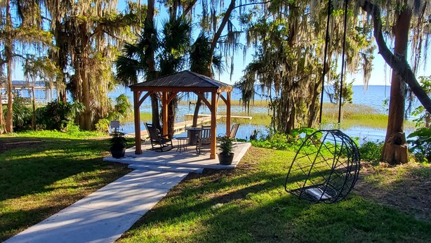 A gazebo with outdoor seating, a pathway, and a view of a body of water. - Lakefront Magic Wilderness Cabin (Leesburg)