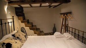 A bedroom with a bed, a staircase, and a wooden headboard.
