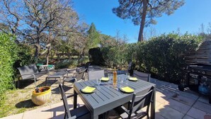 Eine Terrasse im Freien mit einem für vier Personen gedeckten Tisch, umgeben von Stühlen, einem Grill und einer Sitzecke mit einer Bank.