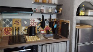 Une cuisine équipée d’une cuisinière, d’un évier et d’étagères remplies de bocaux.