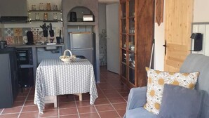 Un espace de vie compact comprenant un coin cuisine, une table à manger, un canapé et un meuble de rangement.
