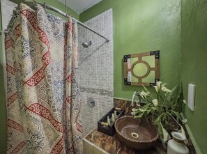 Bathroom features a shower, shower curtain with geometric pattern, and a decorative mirror.