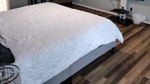 Ein Schlafzimmer mit einem großen Bett, einem Deckenventilator, einem Fernseher, einem Sessel und einem kleinen Tisch mit einer Pflanze.
