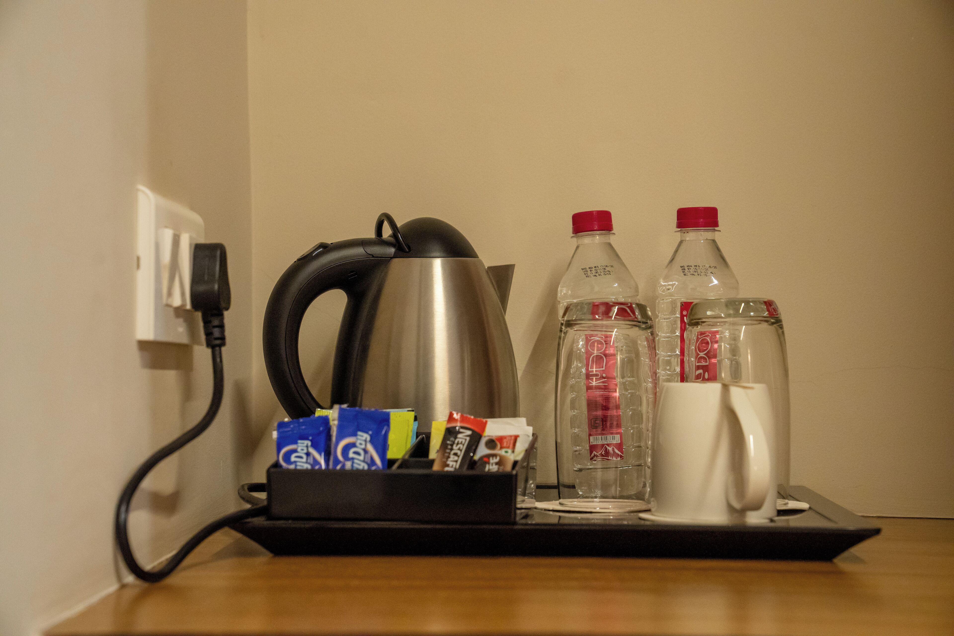 Eine Kaffeemaschine, zwei Wasserflaschen, eine Tasse und ein Mehrfachsteckdosenadapter mit Kabeln auf einem Tisch.