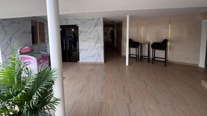 A spacious living area with a marble wall, a black refrigerator, and two black chairs. - PRESKEN HOTEL ALADE (Lagos)