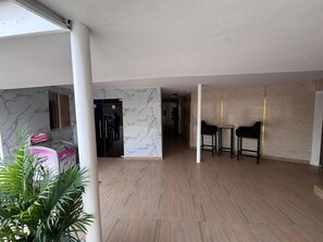 Un vaste espace de vie agrémenté d’un mur en marbre, d’un réfrigérateur noir et de deux chaises noires.